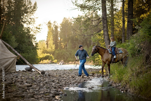 Father guiding his daughter on a horse. photo