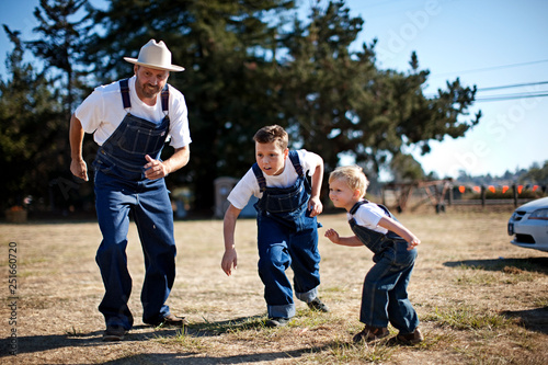 Father and two sons wearing matching denim overalls about to race photo