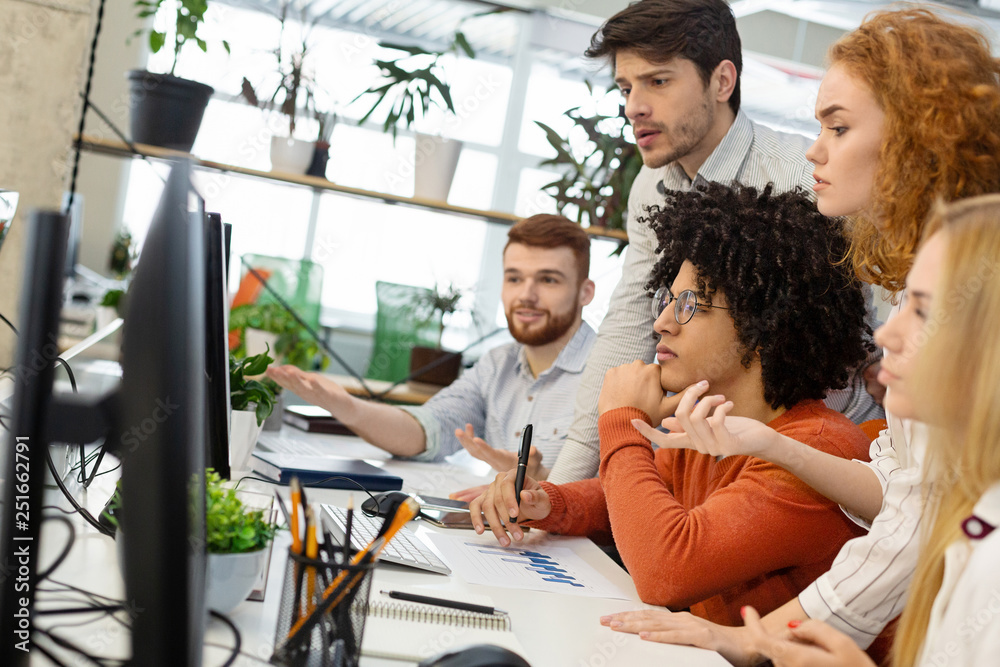 Millennial team working with new project on computer screen Millennial team working with new project on computer screen