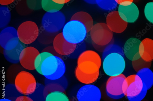 Multi-color blue holiday garland. Garland is blurred. Many big colorful round lights. Fully defocused photo. Blurred background and foreground. Holiday mood. New Year and Christmas is coming.
