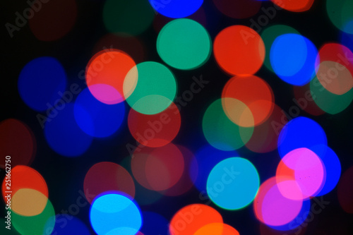 Multi-color blue holiday garland. Garland is blurred. Many big colorful round lights. Fully defocused photo. Blurred background and foreground. Holiday mood. New Year and Christmas is coming.