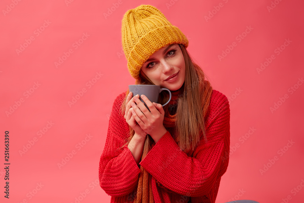 Beautiful teenage girl in warm cozy sweater with cup of hot drink. Red background. Studio Beautiful teenage girl in warm cozy sweater with cup of hot drink. Red background. Studio