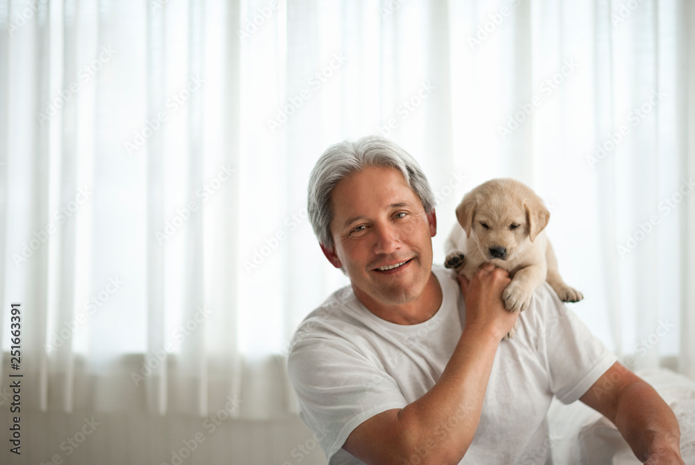 Smiling middle aged man with Labrador puppy on his shoulder. Smiling middle aged man with Labrador puppy on his shoulder.