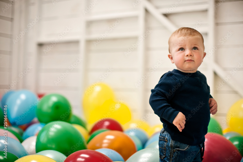 Little boy standing in a room full of balloons. Little boy standing in a room full of balloons.