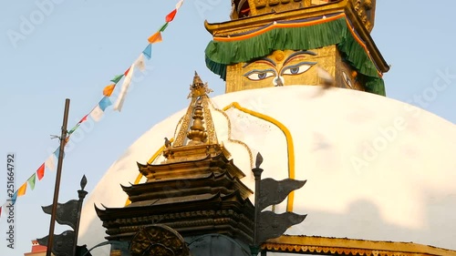 Colorful prayer flags wawing in the wind over Stupa temple, Holy Pagoda, symbol of Nepal and Kathmandu with Buddha's Eyes. Sunset ligth. tibetan buddhism. Pigeons flying over ancient architecture.