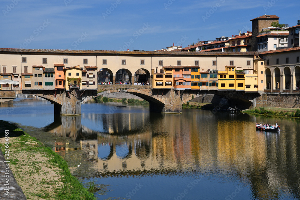 Tourists on the boat under the Ponte Vecchio in Florence reflecting on the waters of the river Arno. Italy.