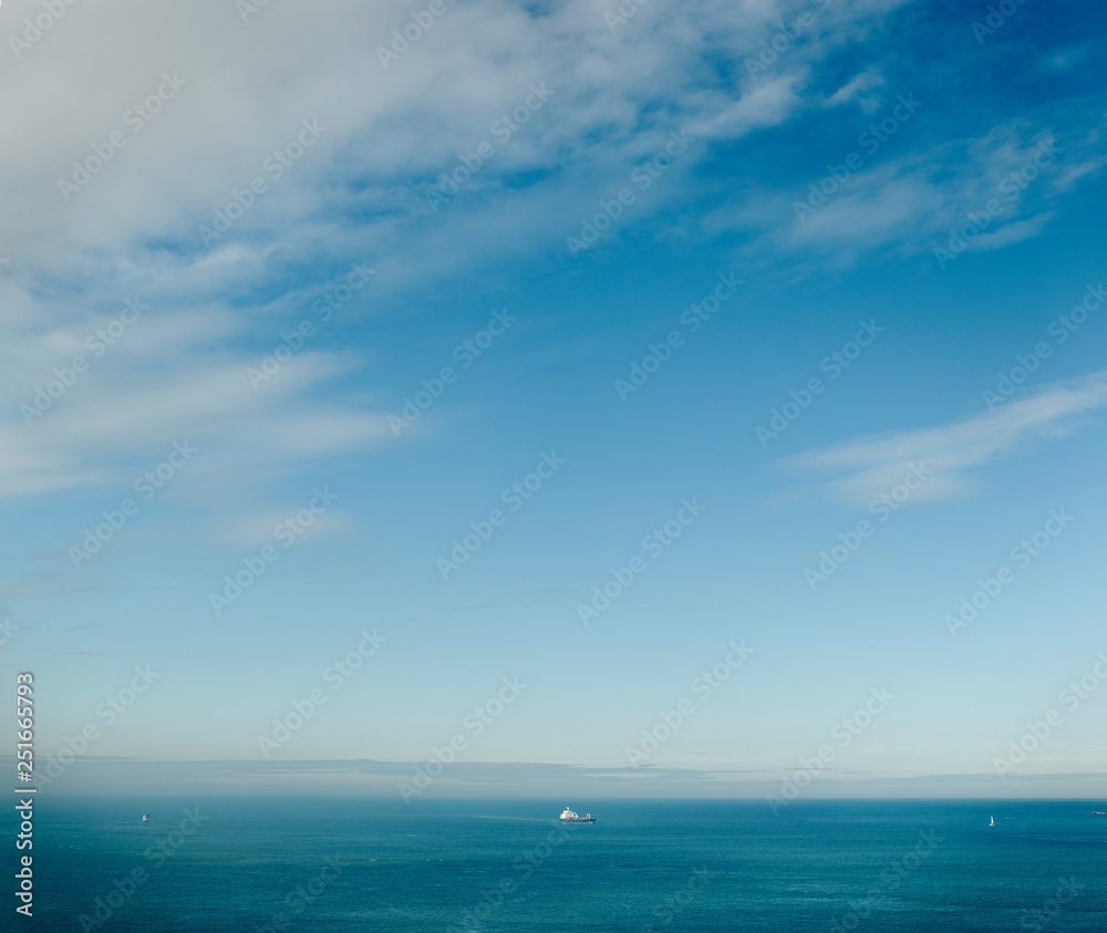 Cargo ship and a sailboat in a vast open sea. Cargo ship and a sailboat in a vast open sea.