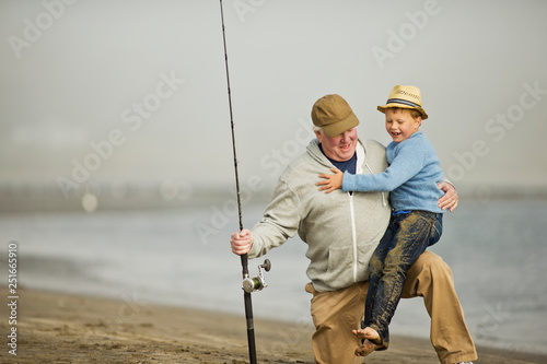 Senior man playing on a beach with his young grandson.
