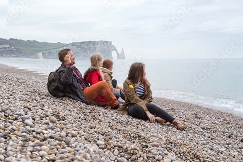 Dad with mom and two daughters sitting on the beach of Etretat
