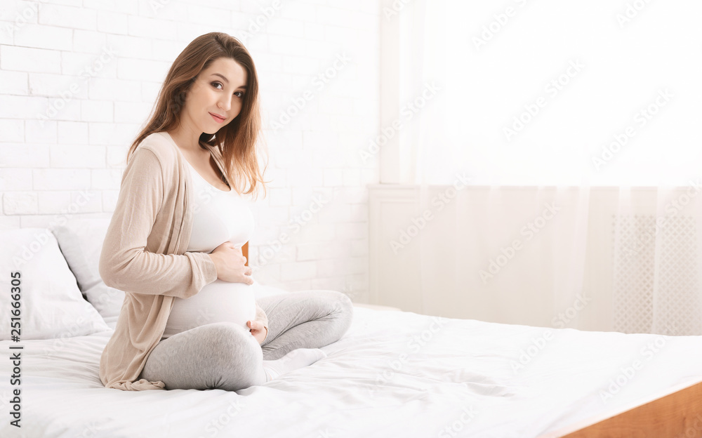 Pregnant happy woman touching her belly in bed Pregnant happy woman touching her belly in bed