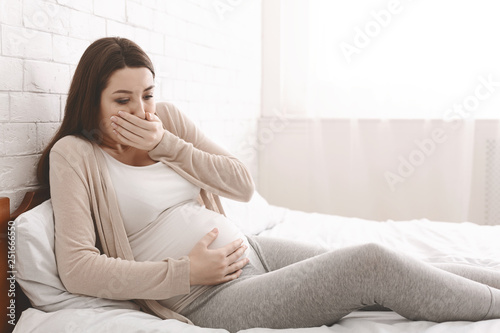 Fotografie Pregnant woman suffering from morning nausea in bed