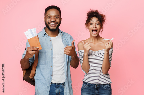 Excited couple holding flying tickets and showing thumbs up