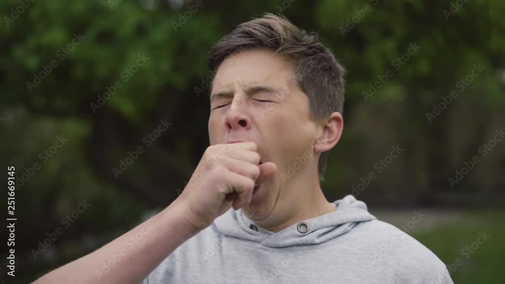 Bored, tired, young white teenager yawning whilst isolated outdoors in his backyard Bored, tired, young white teenager yawning whilst isolated outdoors in his backyard