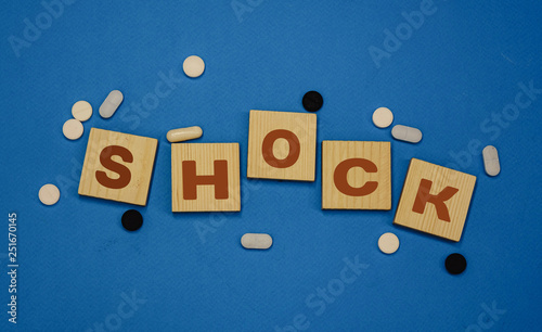 the word shock on wooden cubes blue background pills black and white pills