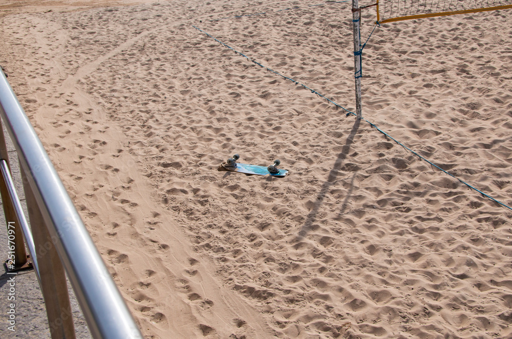 skateboard lies turned upside down on a sandy beach skateboard lies turned upside down on a sandy beach