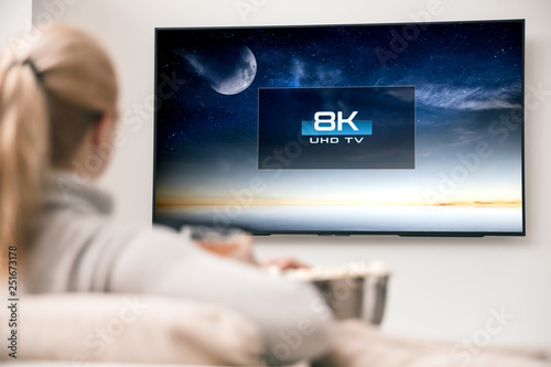 Woman watches tv with 8k ultra hd resolution. Picture on the screen created in graphic software.