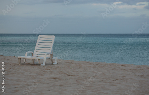 A White Beach Chair on the Beautiful Sunset Beach. Ahtlantic Ocean on a Background