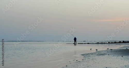 Fisherman in Ria Formosa wetlands natural park, dusk seascape, shot at Cavacos beach. Algarve. Portugal.