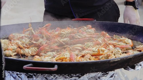 Crayfish cooking in a big cauldron. Cooking process of sea food at the street food festival. Lobsters roast in a big saucepan. Chef preparing lobsters in a big wok, close up.
