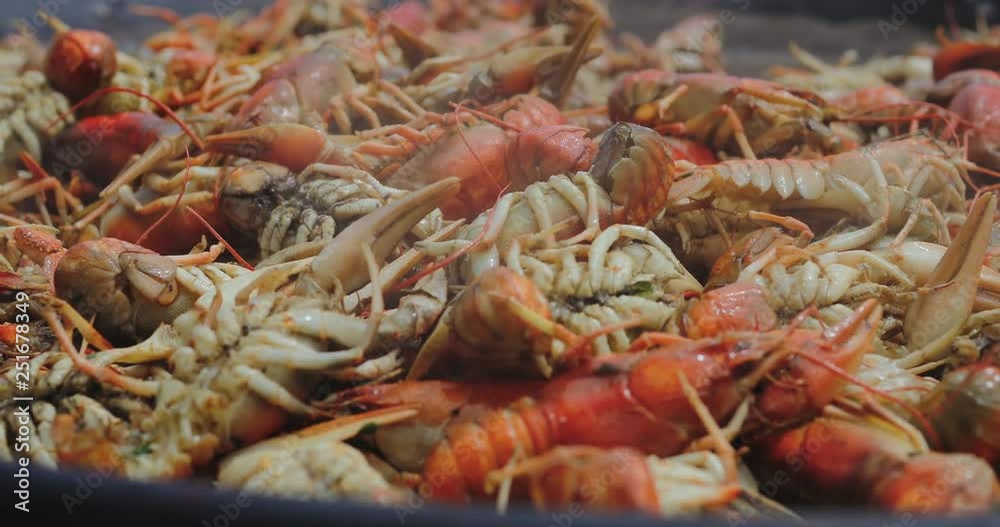 Crayfish cooking in a big cauldron. Cooking process of sea food at the street food festival. Lobsters roast in a big saucepan. Chef preparing lobsters in a big wok, close up. Crayfish cooking in a big cauldron. Cooking process of sea food at the street food festival. Lobsters roast in a big saucepan. Chef preparing lobsters in a big wok, close up.