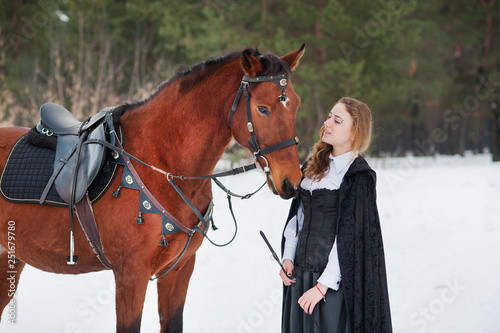 Beautiful girl in historical clothes next to a horse