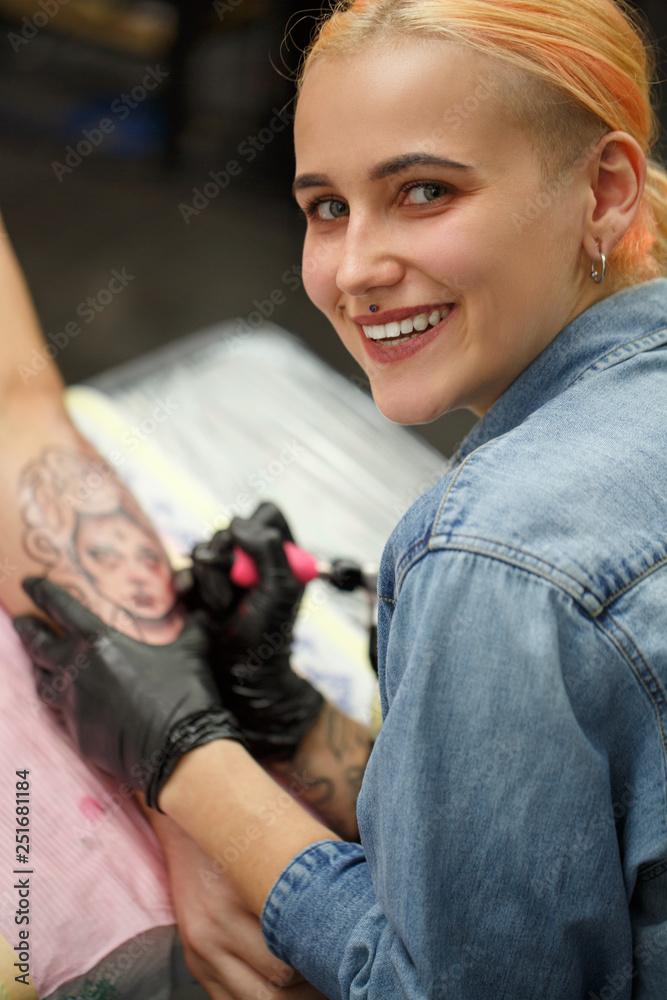 Beautiful female tattooist with piercing above lips smiling. Tattoo