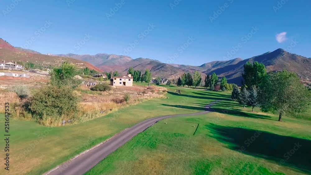man tee off to follow ball and view mountains. Drone follows the ball as the man tees off at the green course. Beautiful aerial shot of trees, mountains and villa. man tee off to follow ball and view mountains. Drone follows the ball as the man tees off at the green course. Beautiful aerial shot of trees, mountains and villa.