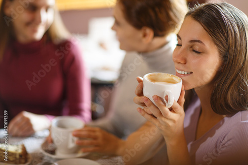 Girl, smiling and holding cup of hot coffee at bright cafe.