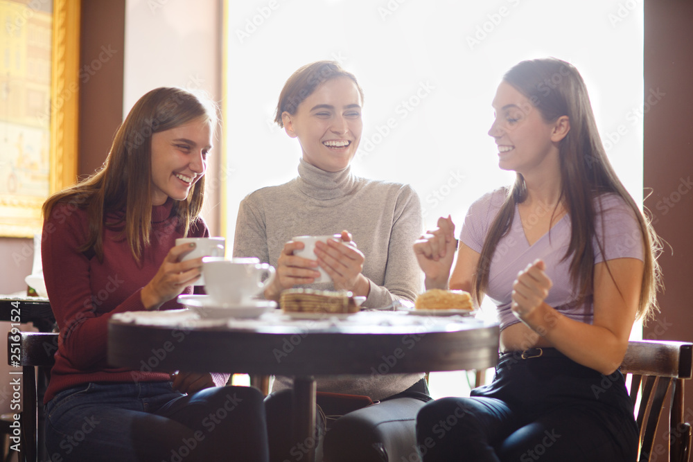 Three charming girls drinking coffee and eating cakes at restaurant. Three charming girls drinking coffee and eating cakes at restaurant.