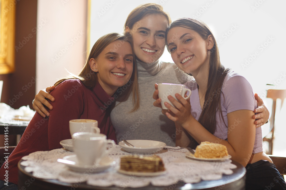 Three women sitting together in cafe and embracing with each other. Three women sitting together in cafe and embracing with each other.