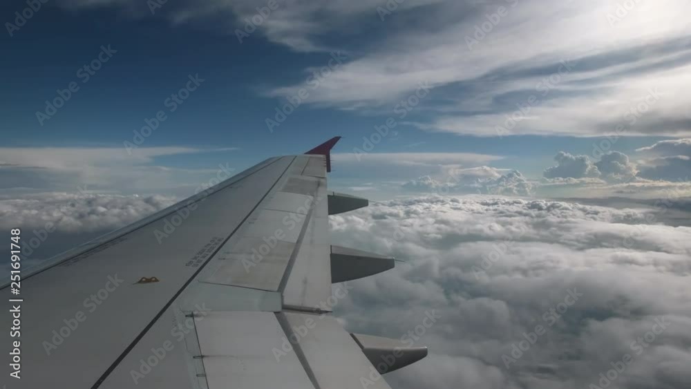 Flight of the plane on a flight level, against the background of blue sky and textural volumetric clouds. The view from the cockpit of the angle of view back, in the foreground a gray wing of an Flight of the plane on a flight level, against the background of blue sky and textural volumetric clouds. The view from the cockpit of the angle of view back, in the foreground a gray wing of an