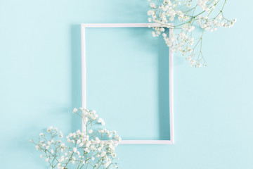Flowers composition romantic. White gypsophila flowers, photo frame on pastel blue background. Valentine's Day, Easter, Birthday, Happy Women's Day, Mother's day. Flat lay, top view, copy space