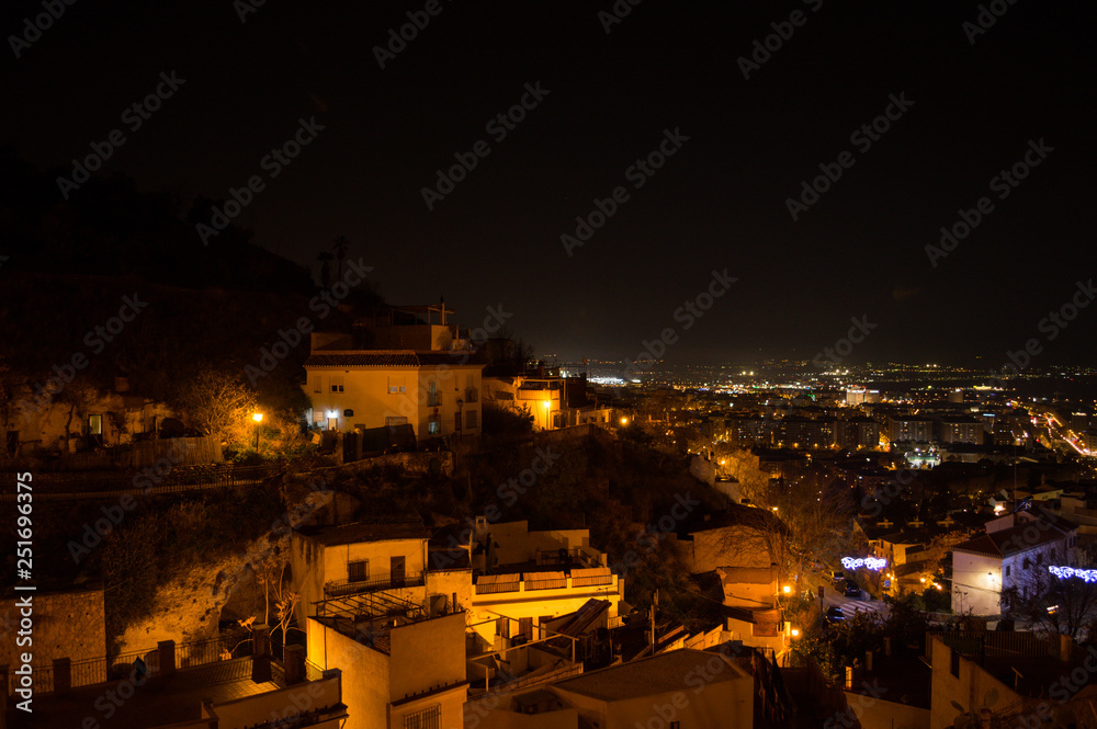Whitewashed Houses and Cityscape in Granada, Spain as seen from Barranco del Abogado at Night