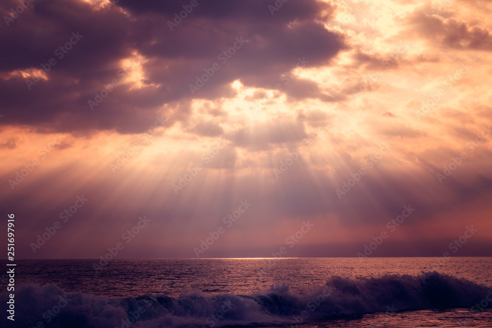 Sunset over the sea. Beautiful clouds through which the rays of the sun make their way.