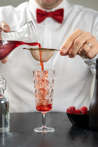 Obraz na płótnie classy fancy bartender mixologist makes prepares alcohol drink cocktail bowtie raspberry w salonie