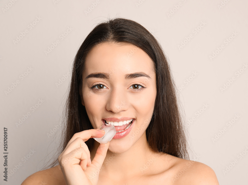 Young woman with ice cube on light background Young woman with ice cube on light background