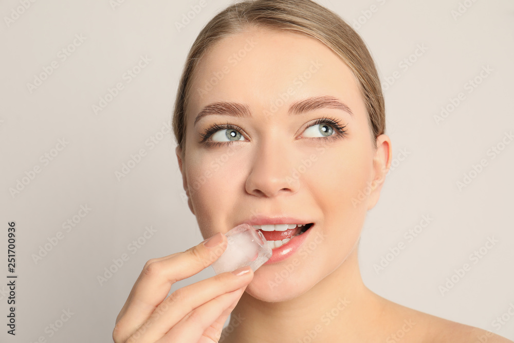 Young woman with ice cube on light background Young woman with ice cube on light background