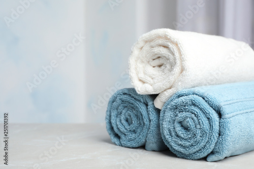 Rolled bath towels on table against blurred background. Space for text
