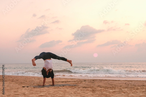 Girl doing yoga on the beach, sunset