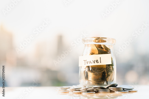 Concepts of retirement planning and financial. Coins in glass money jar with travel label.