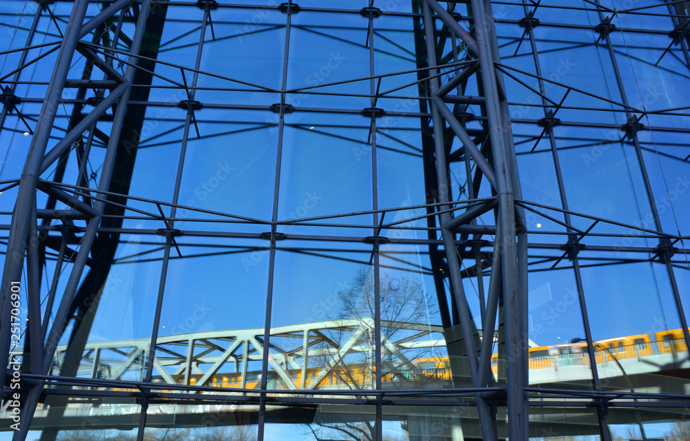 Modern architecture in Berlin, Germany, with an reflection of a yellow subway train crossing on a bridge