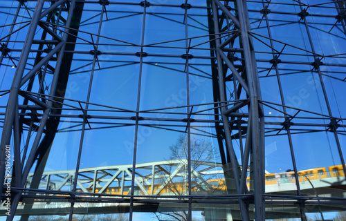 Modern architecture in Berlin, Germany, with an reflection of a yellow subway train crossing on a bridge photo