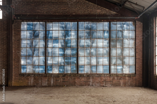 Large blue frosted windows in a loft like space of an abandoned factory with brick walls