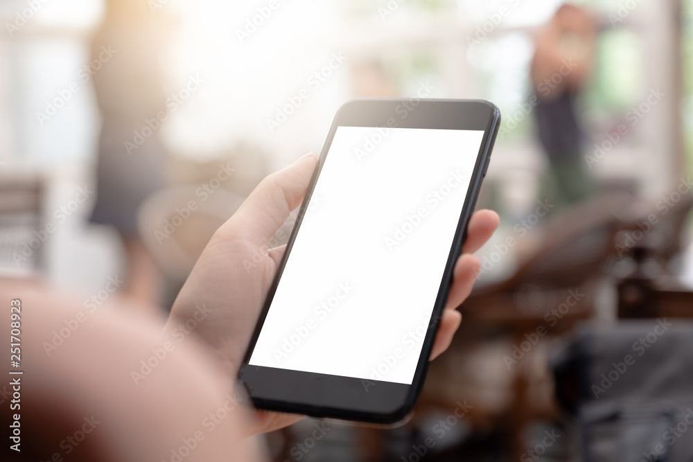 close-up on hand holding phone showing white screen on desk at coffee shop.