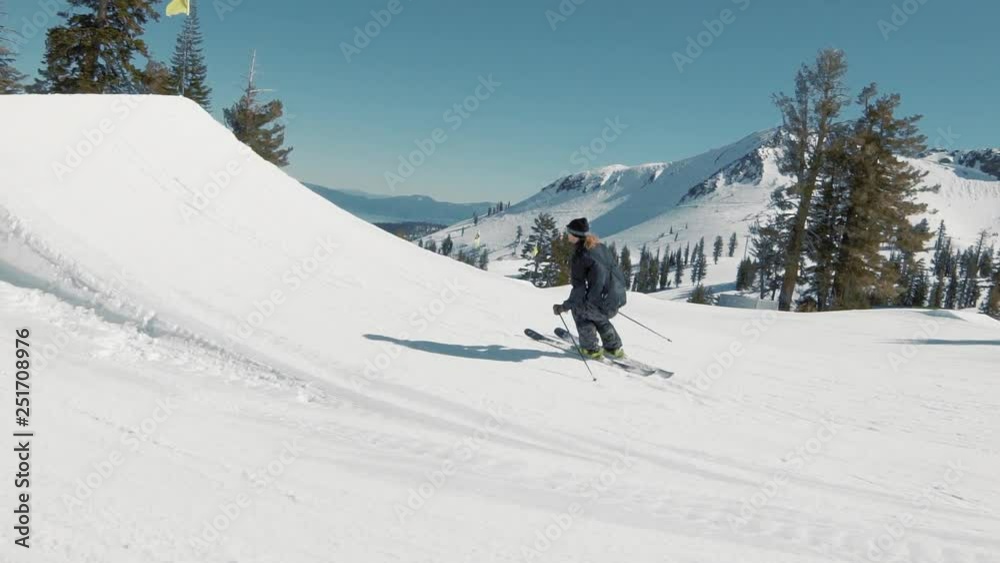 EXTREME ACTION Skier hits huge jump and throws cool trick. Blonde skier races into jump extreme trick in sunny mountains action. Big mountain groomed terrain park at California ski resort EXTREME ACTION Skier hits huge jump and throws cool trick. Blonde skier races into jump extreme trick in sunny mountains action. Big mountain groomed terrain park at California ski resort