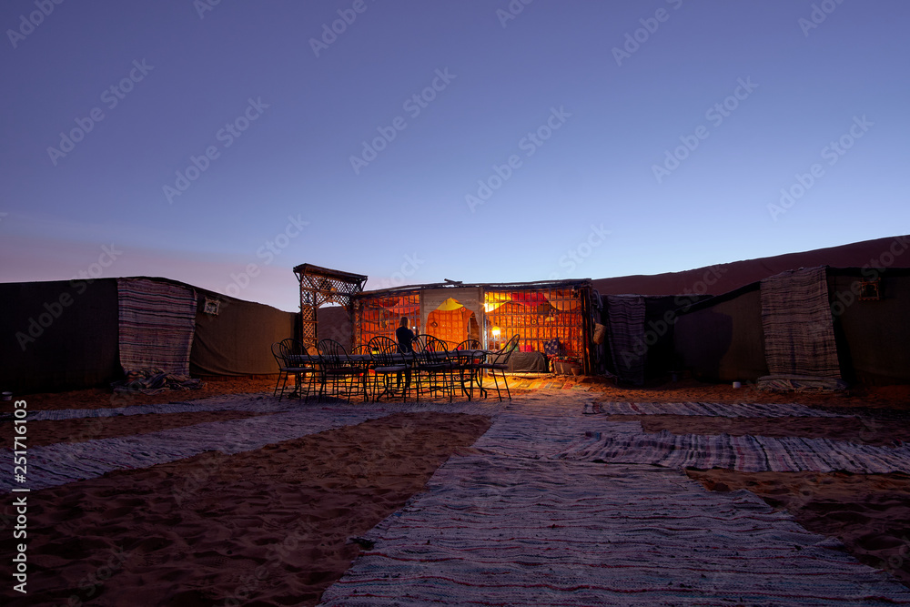 Beautiful evening in a camp with carpets on the sand inside the Sahara ...