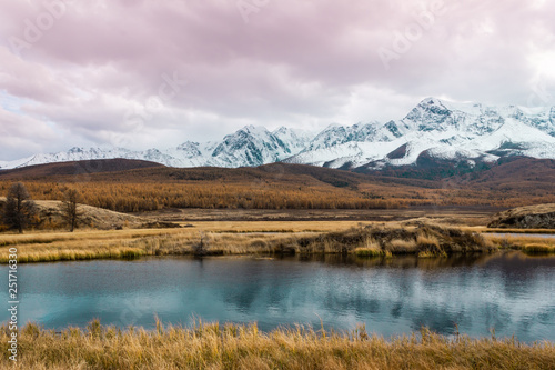 Autumn panorama. View of mountains and lake. Mountain range on horizon. Travel to mountain valley with rivers.