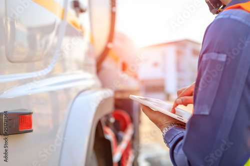 Truck drivers hand holding tablet checking the product list,Driver writing electronic log books,spot focus.