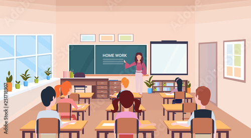 pupils looking at woman teacher writing home work chalk board modern school classroom interior horizontal flat