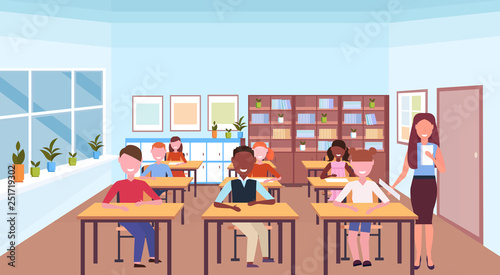 woman teacher reading book during lesson mix race pupils sitting desks education concept modern school classroom interior horizontal flat